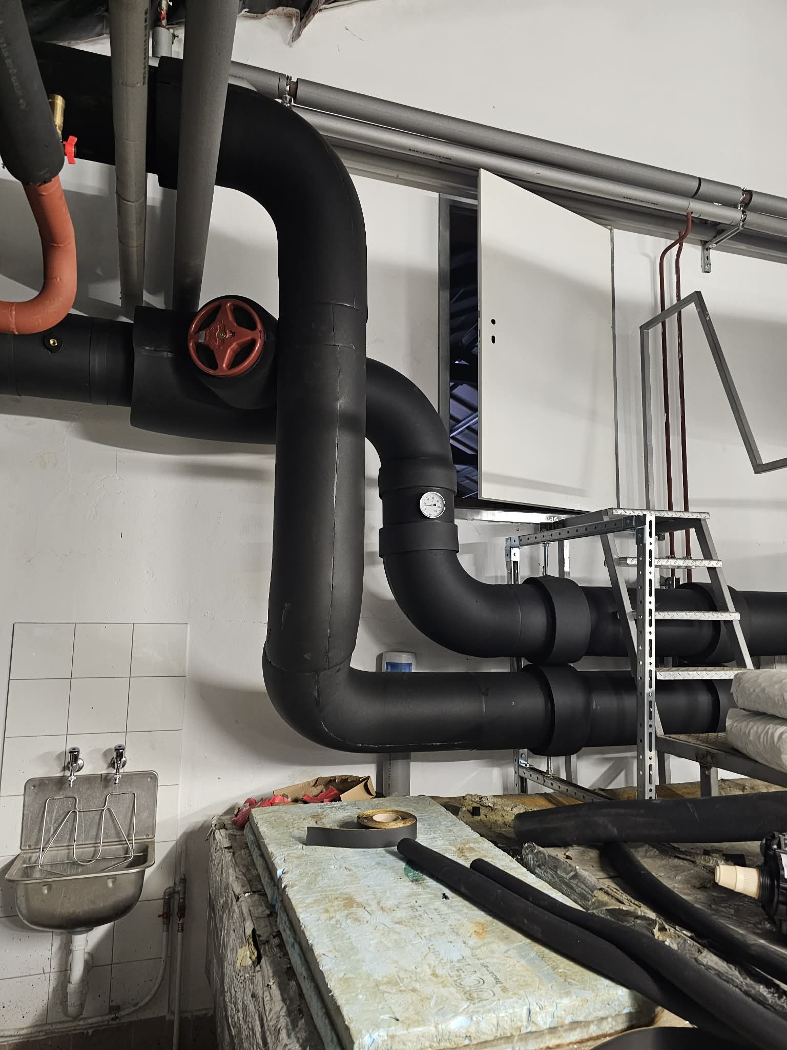 Large industrial boiler room with professionally insulated steam pipes and equipment showing white and orange insulation materials
