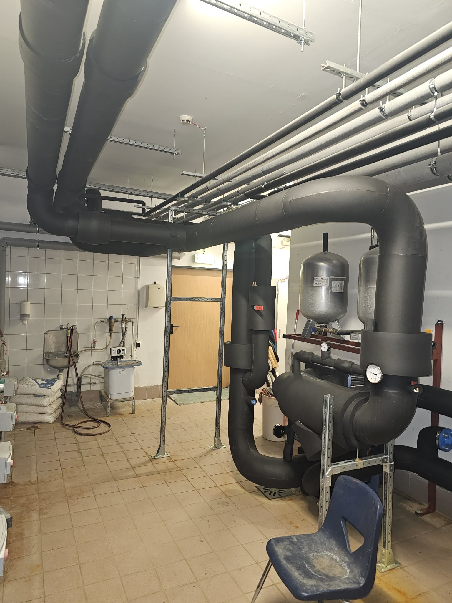 Food processing plant with stainless steel pipes covered in specialized food-grade white insulation materials and temperature control systems