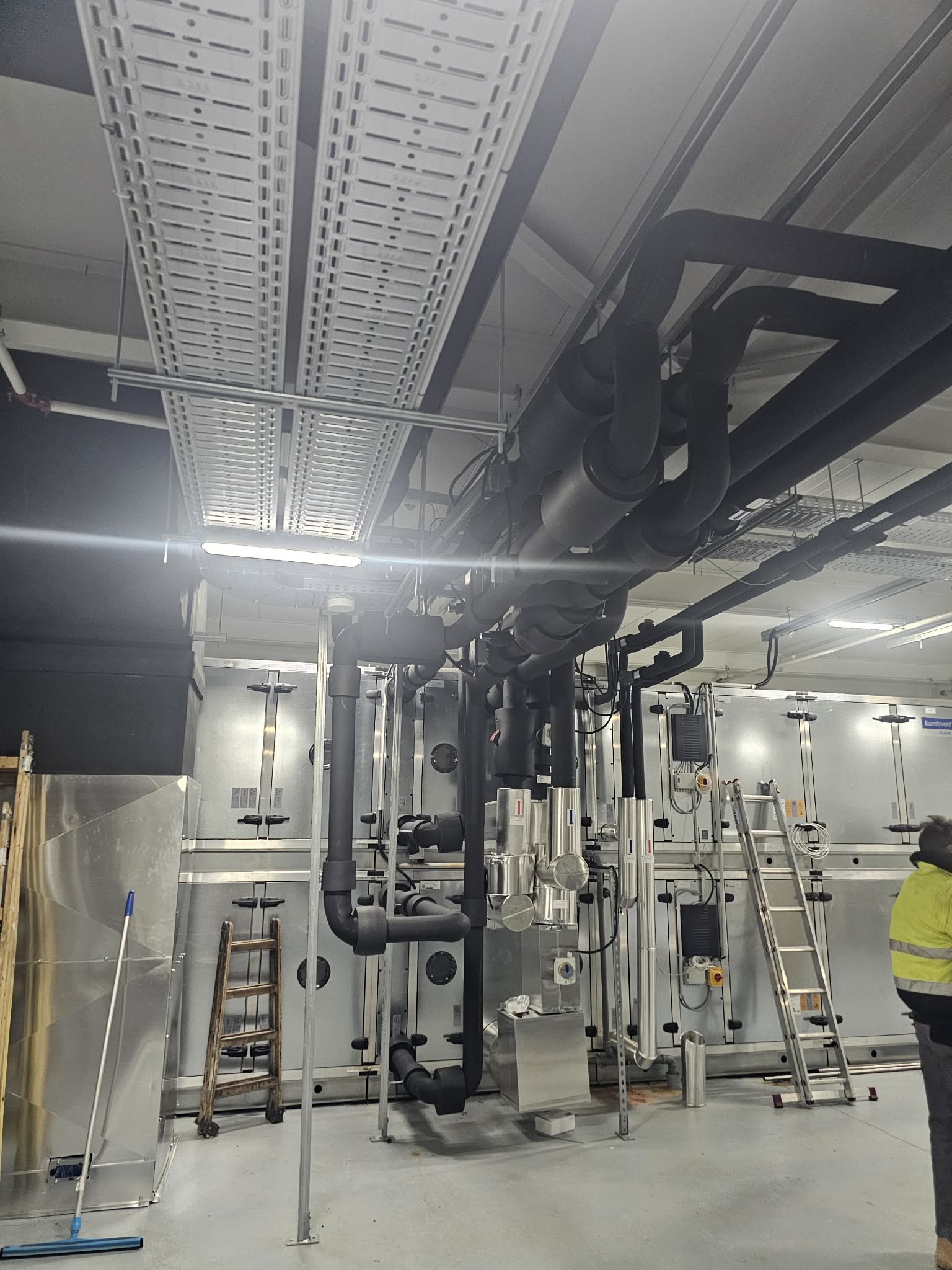 Shopping mall mechanical room with extensive insulated ductwork and pipes showing commercial grade orange and white insulation systems